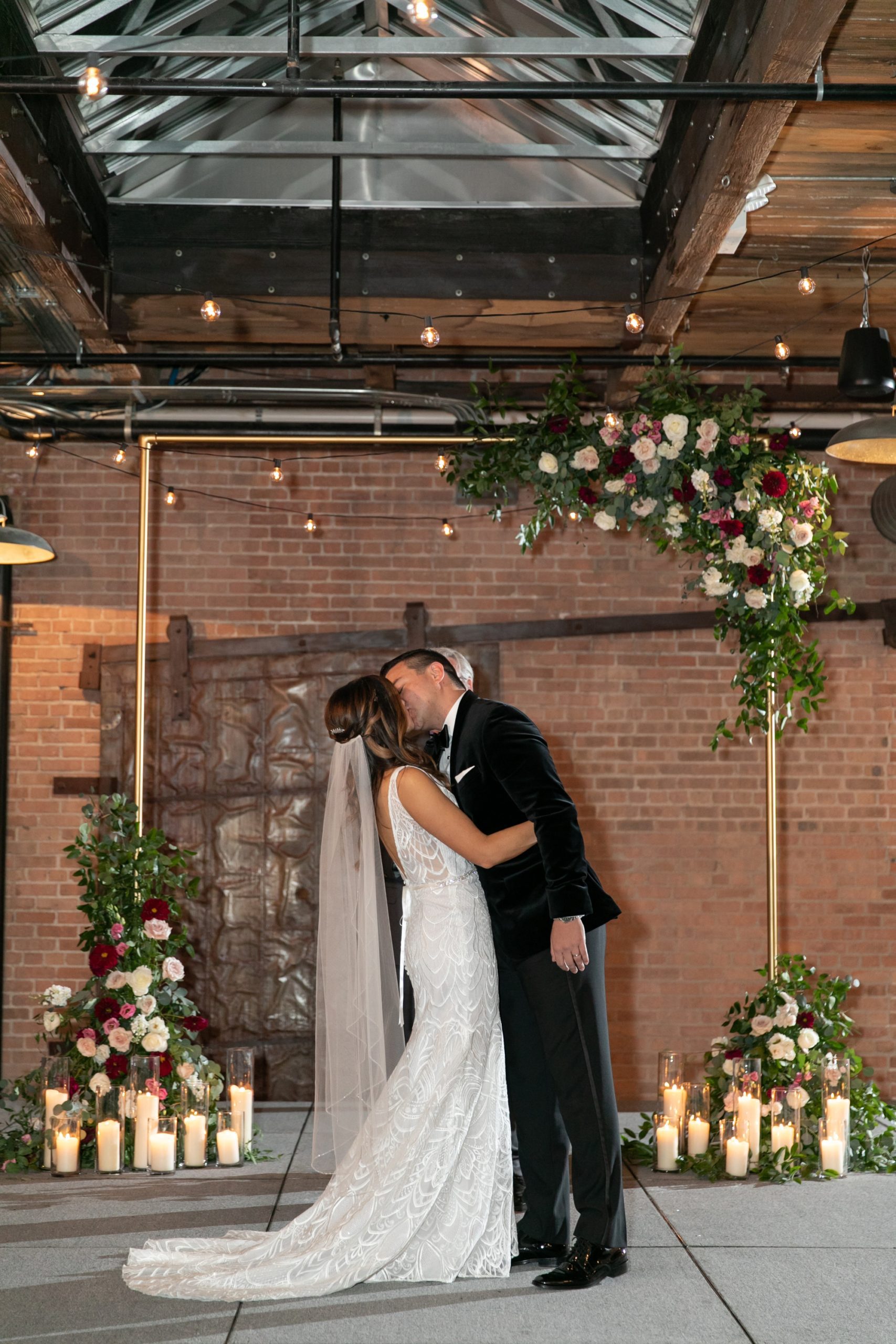 the couple kissed under the floral arch at their Morgan Manufacturing wedding