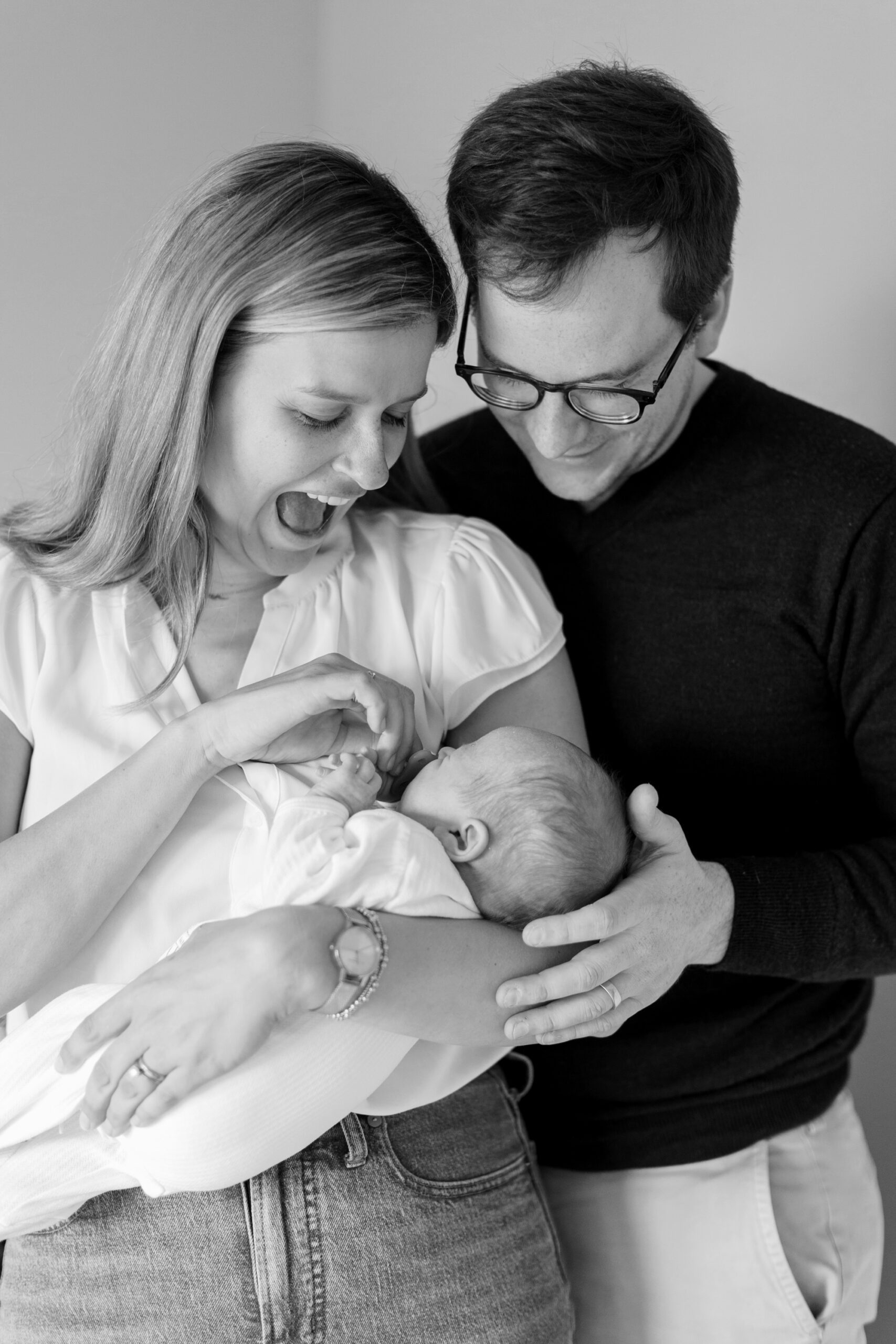 mom and dad laugh at baby during family photos
