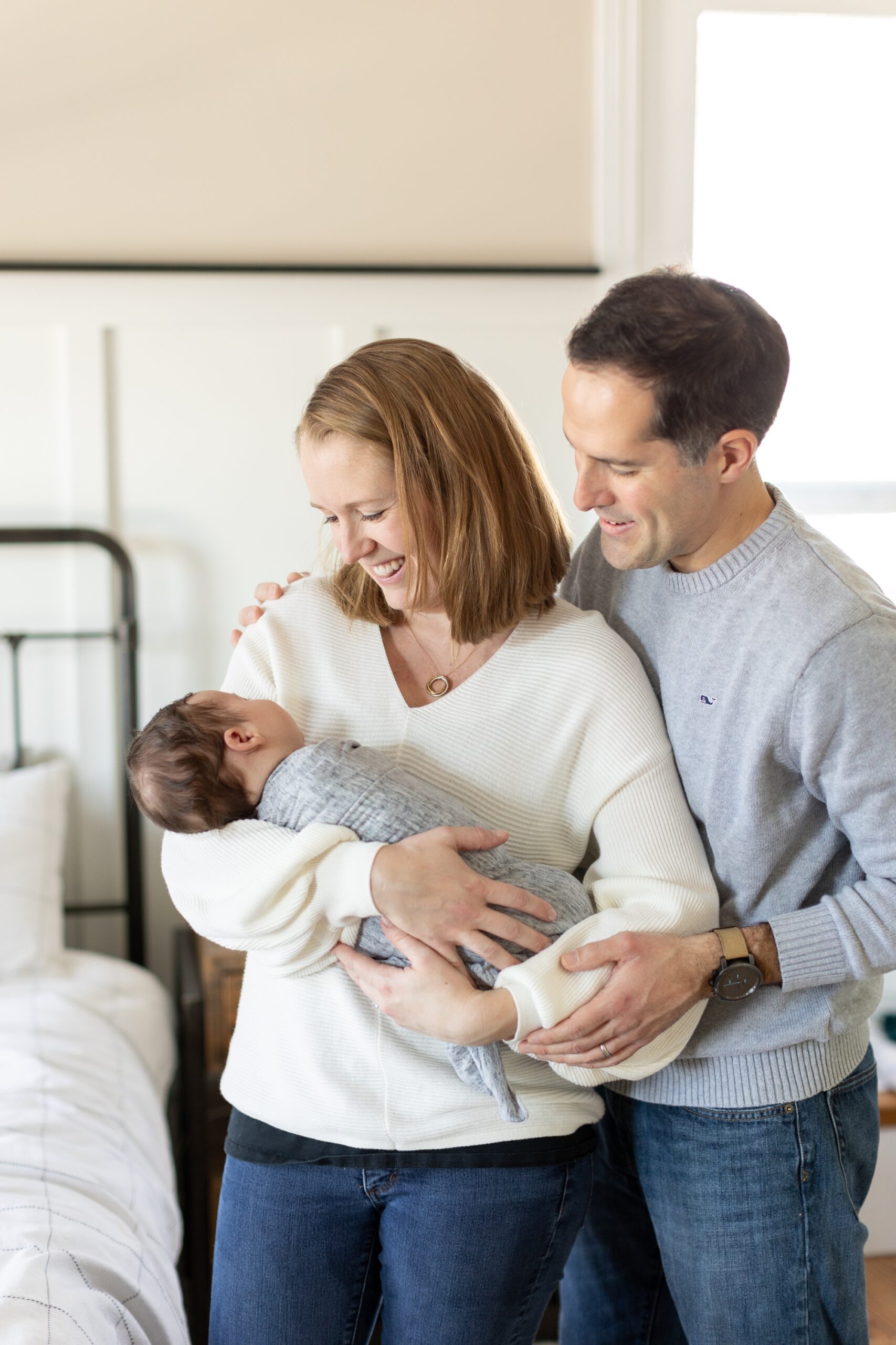 mom and dad smile at newborn during home photo session
