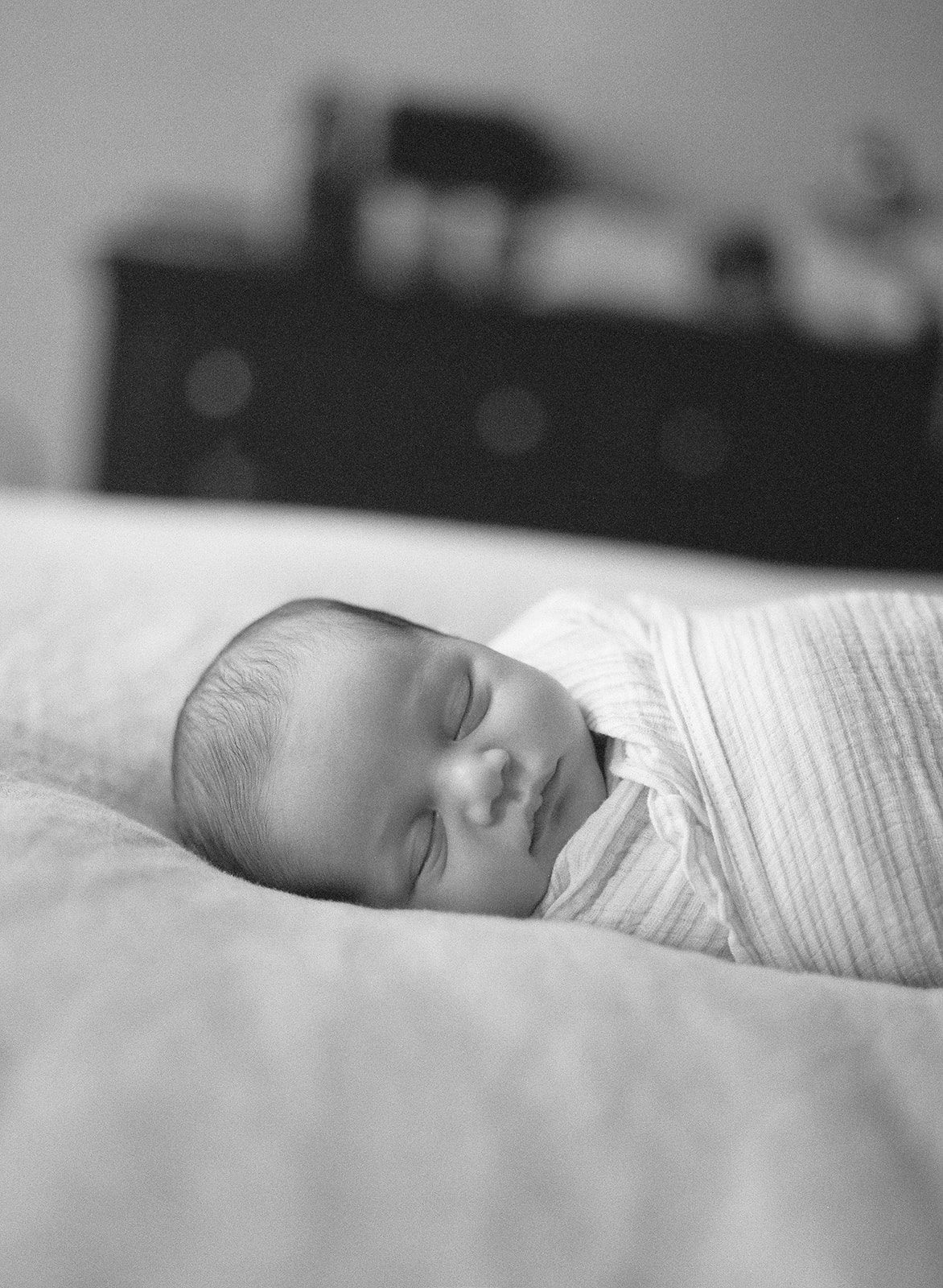 baby in swaddle on bed during Chicago at-home newborn session
