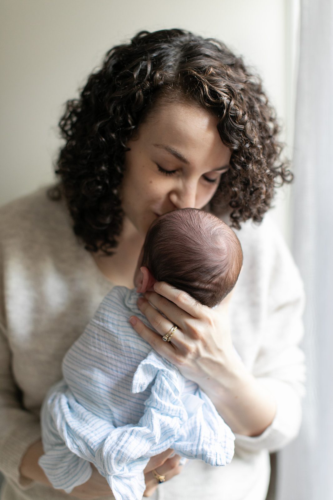 woman kisses newborn baby on the head during the Chicago newborn photoshoot
