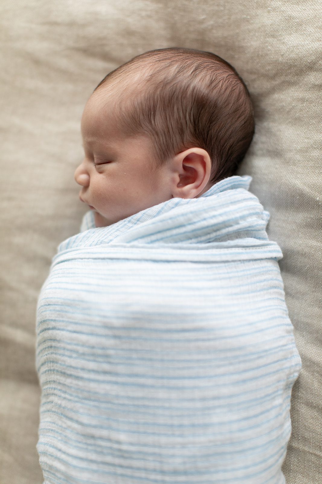 newborn baby is in a swaddle on the bed during Chicago at-home newborn photos
