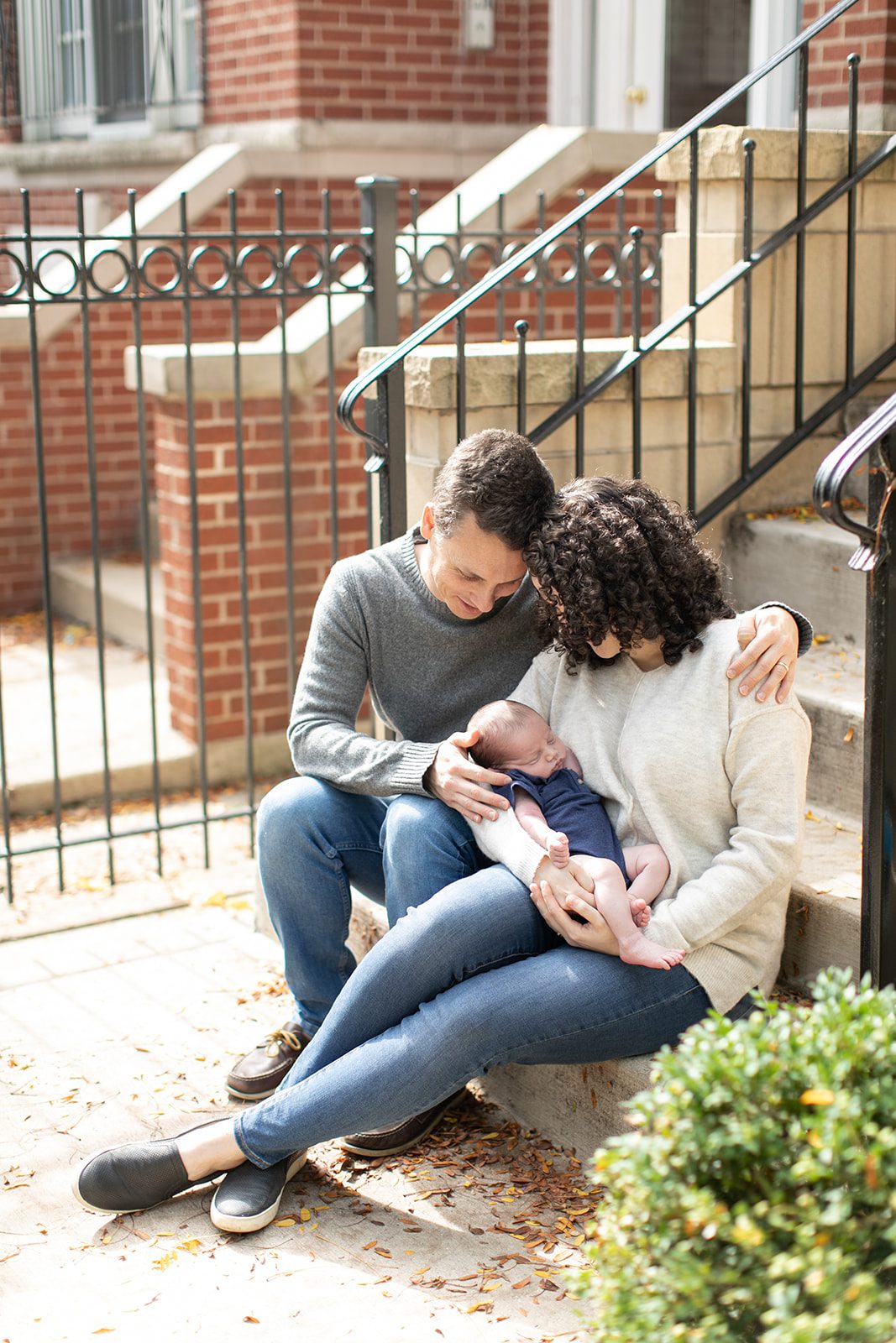 man and woman smile at baby while sitting on their Chicago front porch