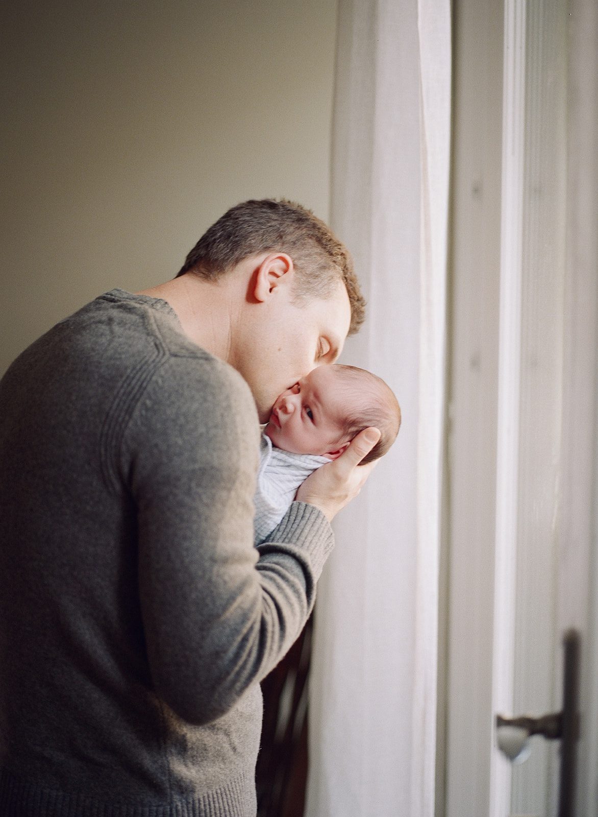 man kisses newborn baby during Chicago at-home newborn photoshoot