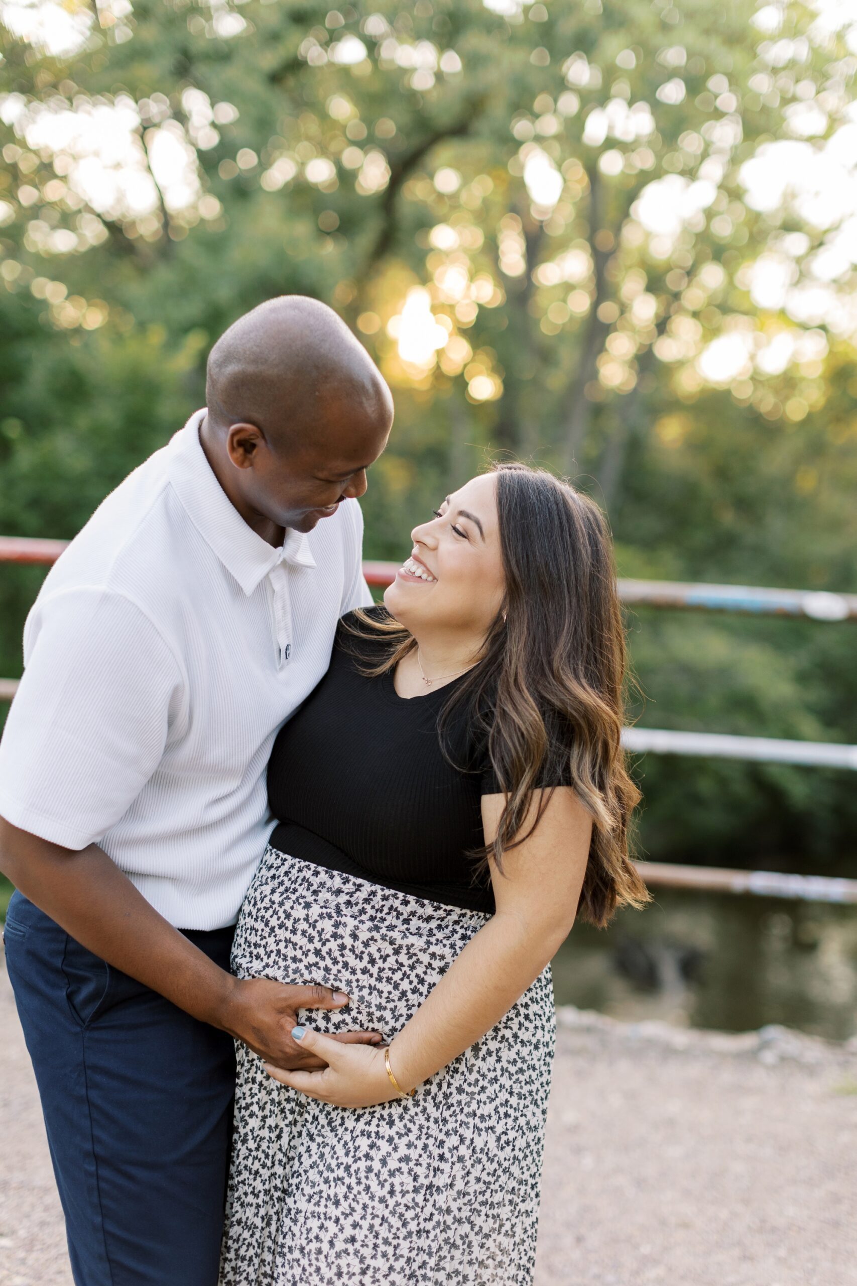 Man and woman smile during Chicago outdoor summer maternity photo session