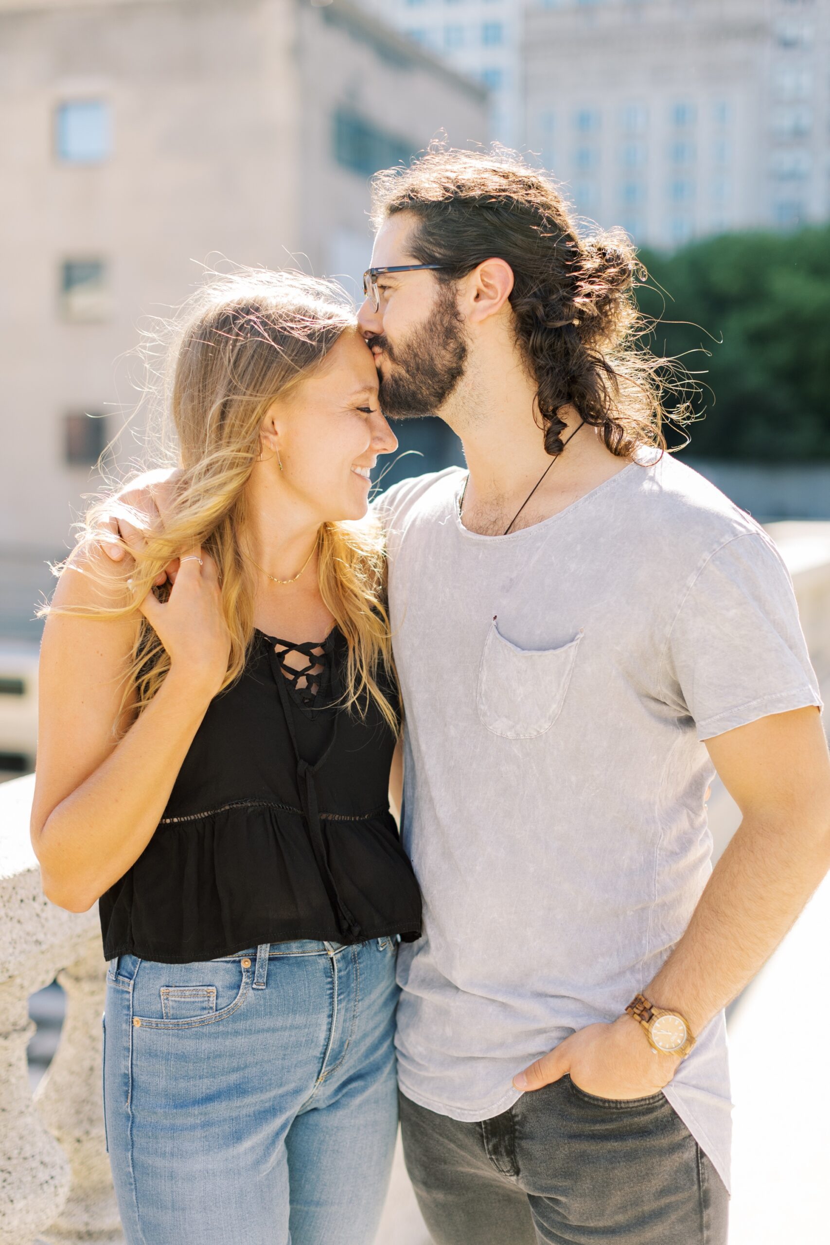Man kisses woman's forehead during summer Chicago engagement photoshoot