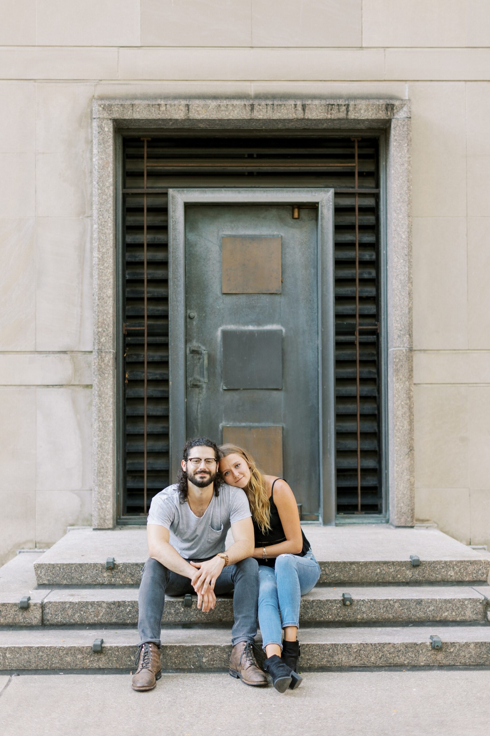 Man and woman smile at the camera during summer city engagement photoshoot