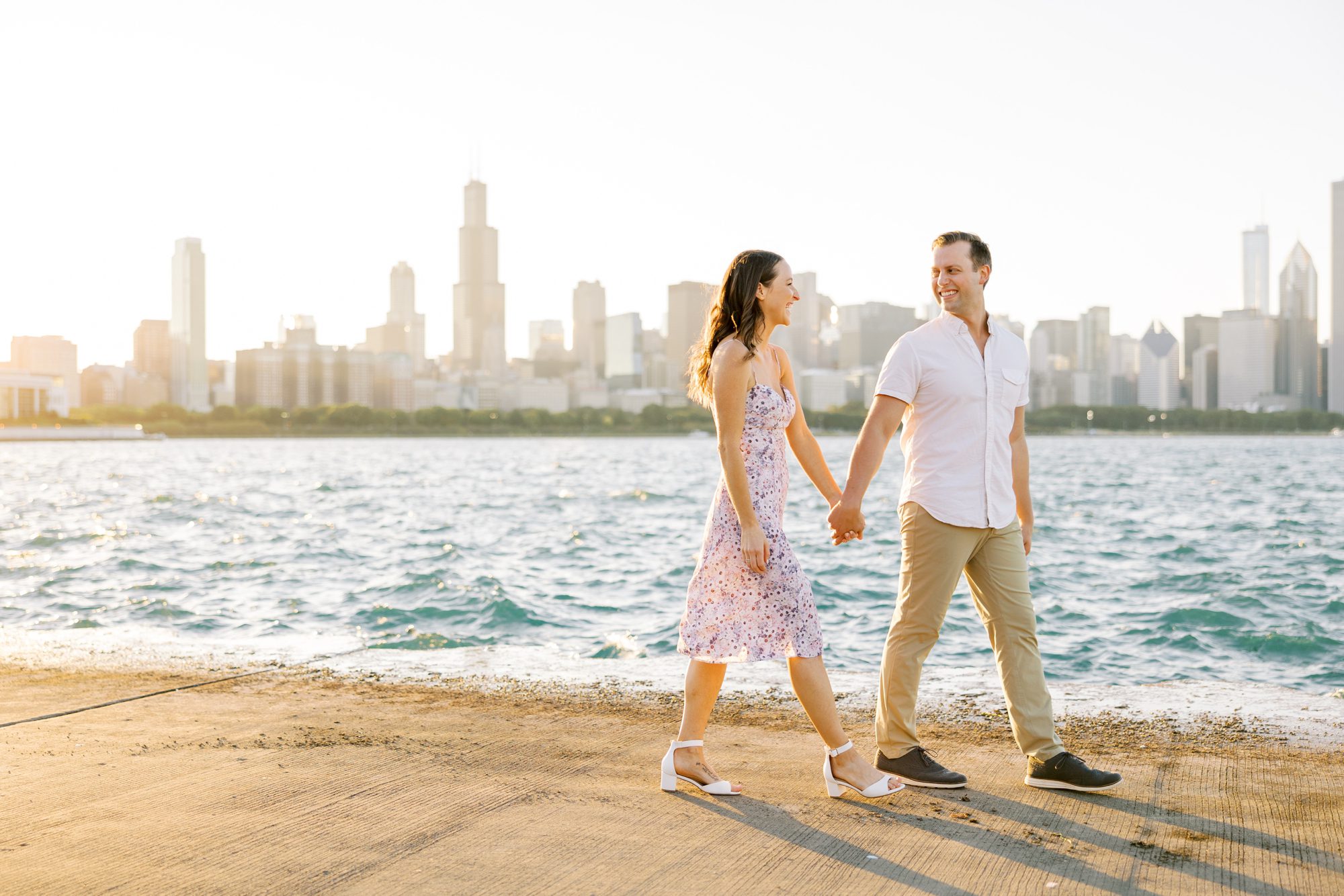 Man and woman hold hands during Chicago museum campus engagement photos with the Chicago skyline backdrop