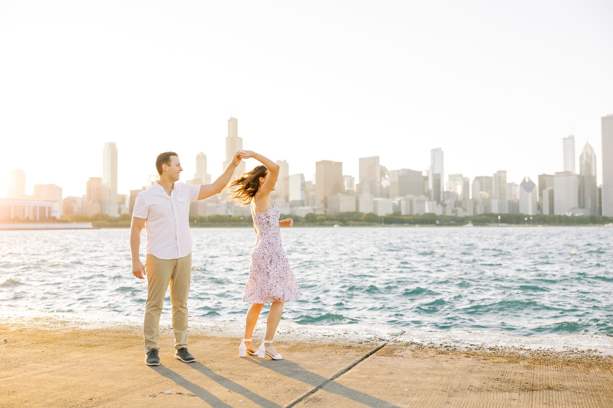 Man and woman dance in front of Chicago skyline backdrop during Chicago Museum Campus engagement photoshoot