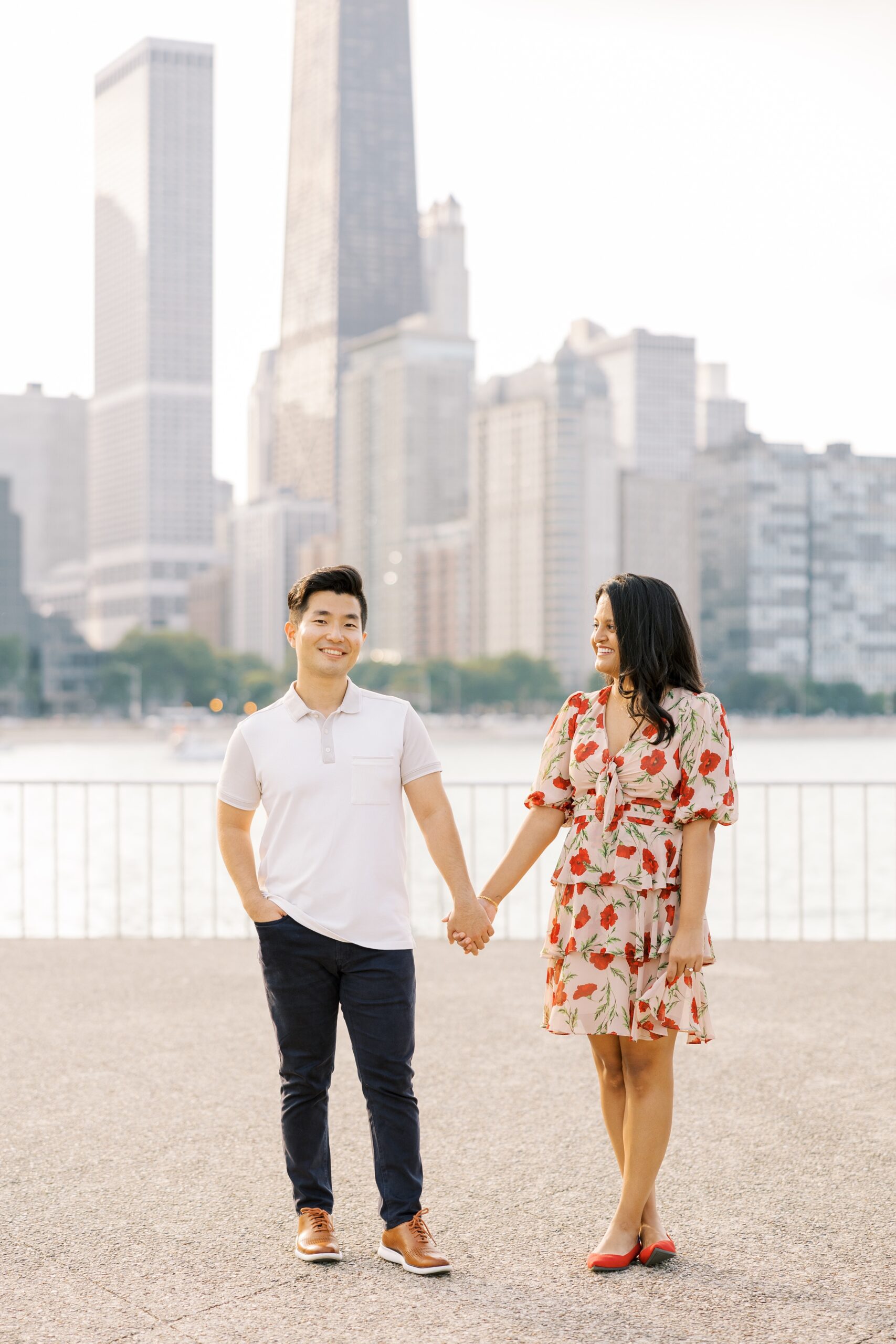 man and woman walk with Chicago skyline behind them during outdoor engagement photos in chicago
