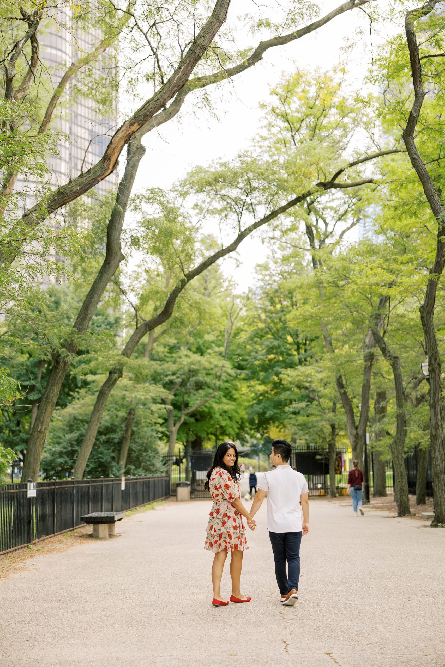 man and woman walk in a park during chicago engagement photo shoot outdoors
