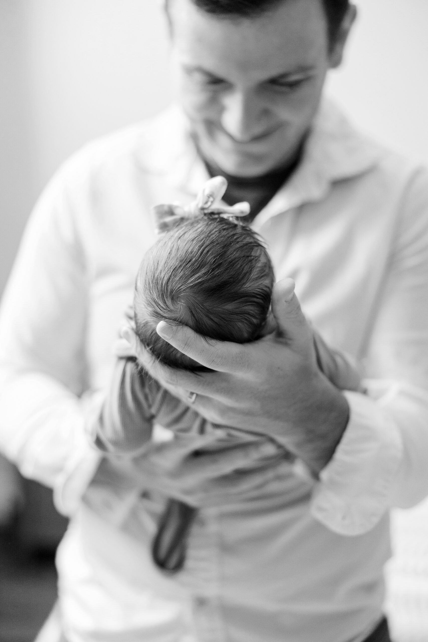 Dad smiles while holding baby during intimate at home newborn session