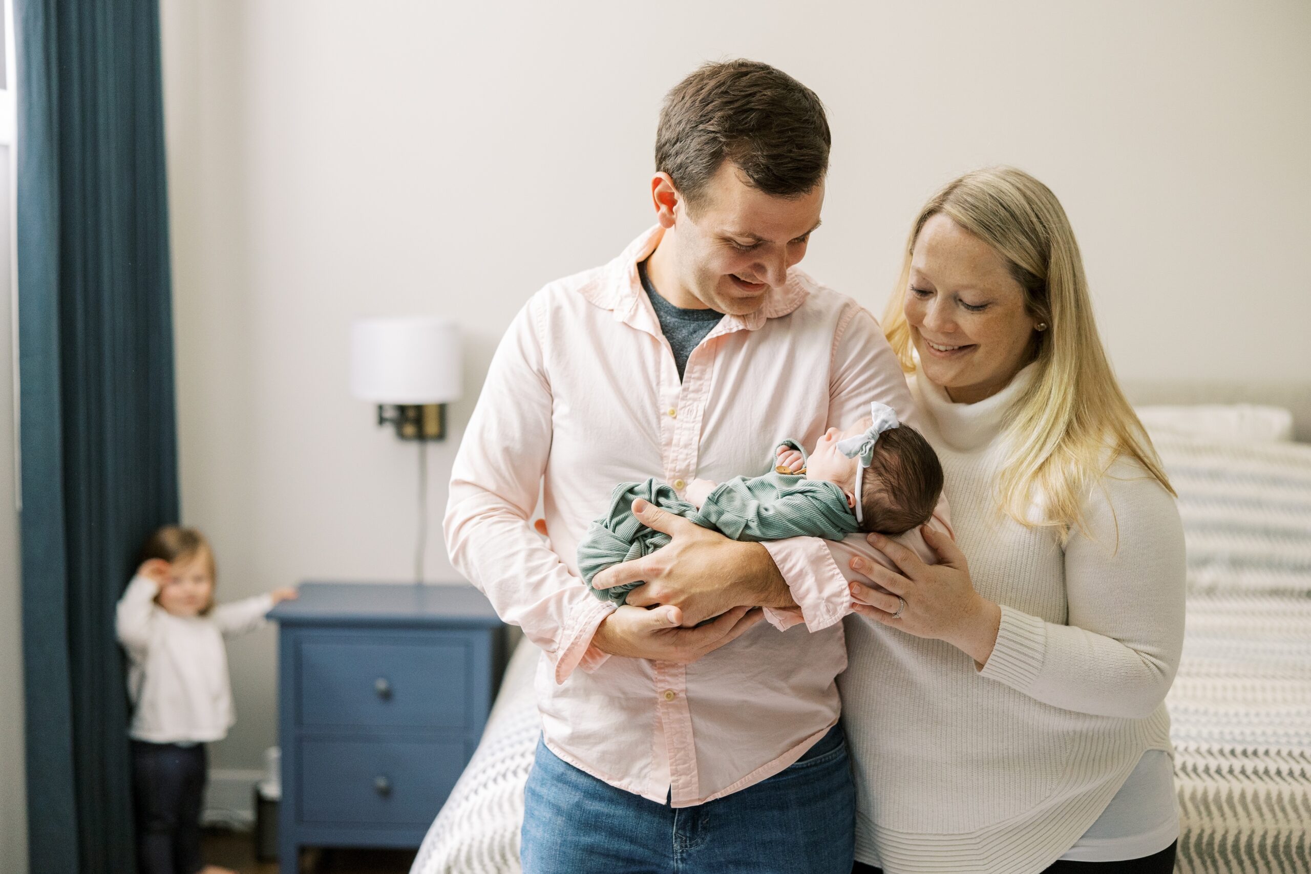 Mom and dad smile at baby during intimate at home newborn photoshoot