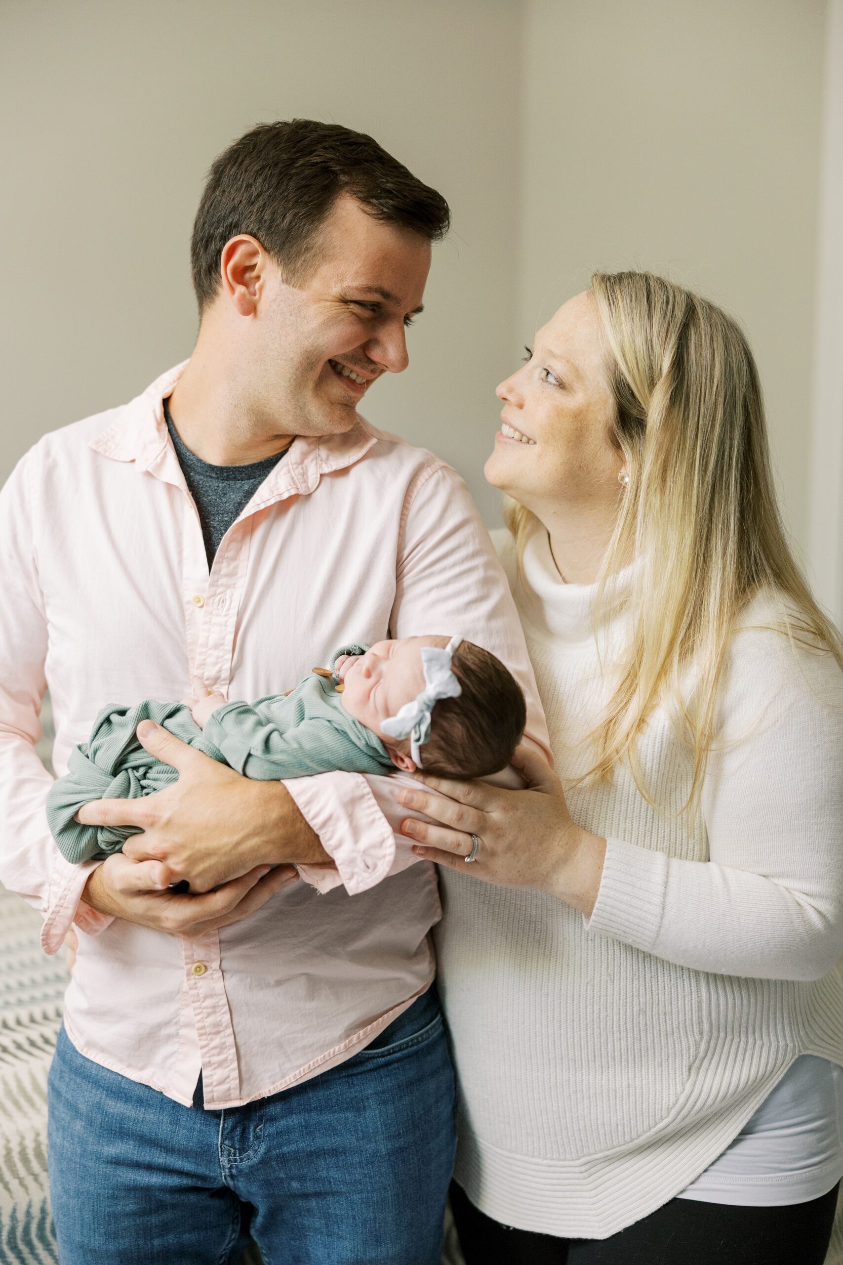 Man and woman smile at each other during at home newborn photo session