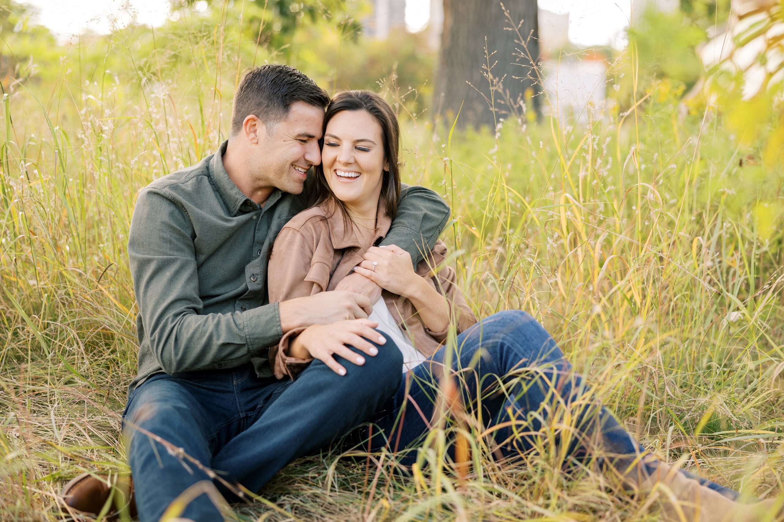 Man and woman sit in tall grass at Lincoln Park Zoo engagement session