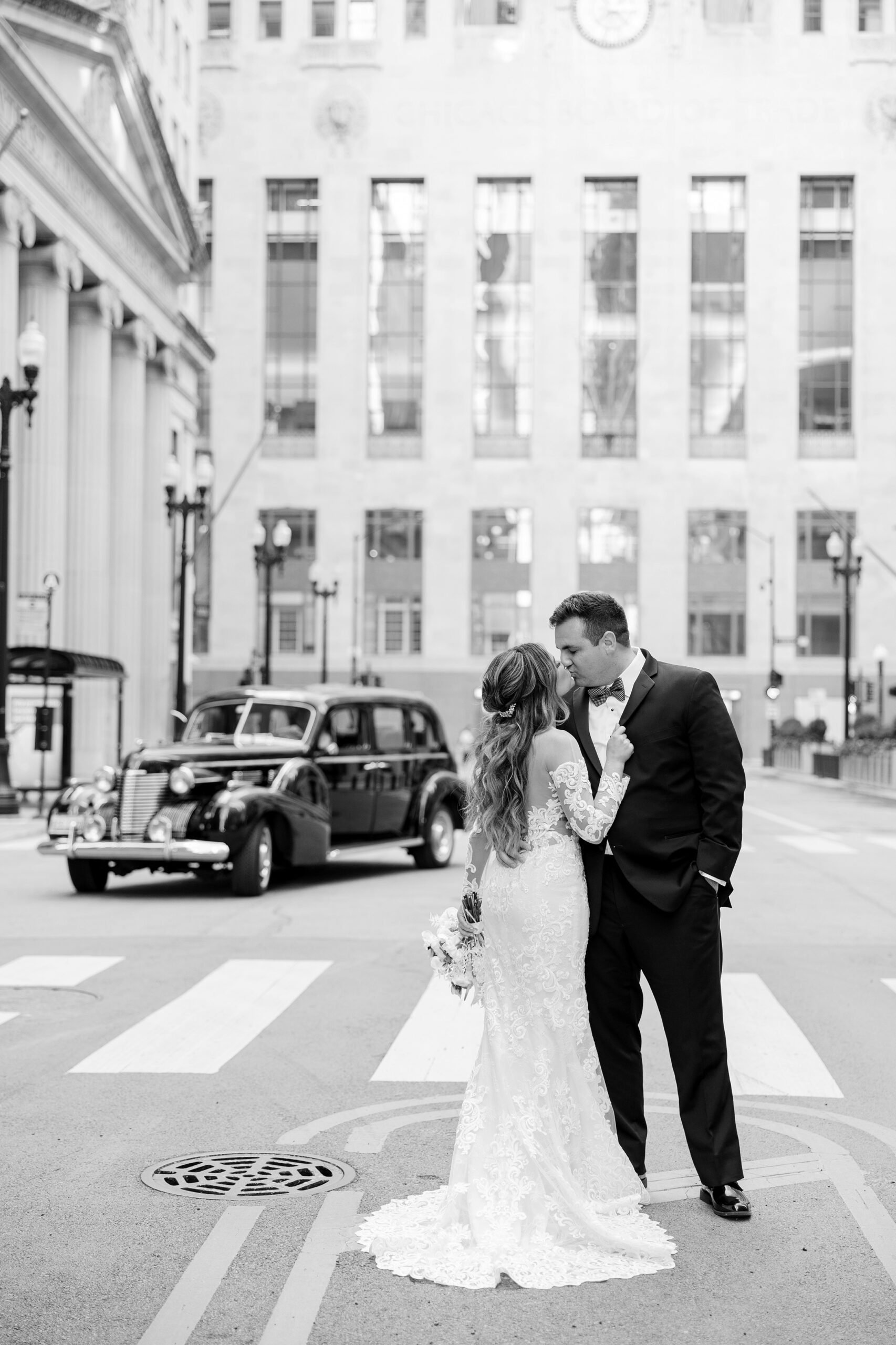 Bride and groom kiss in front of vintage car