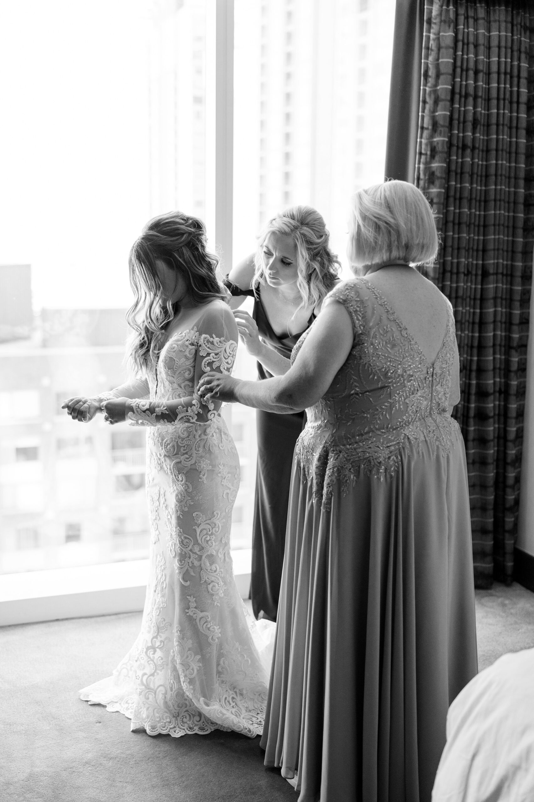 Mother of the bride helping bride into dress