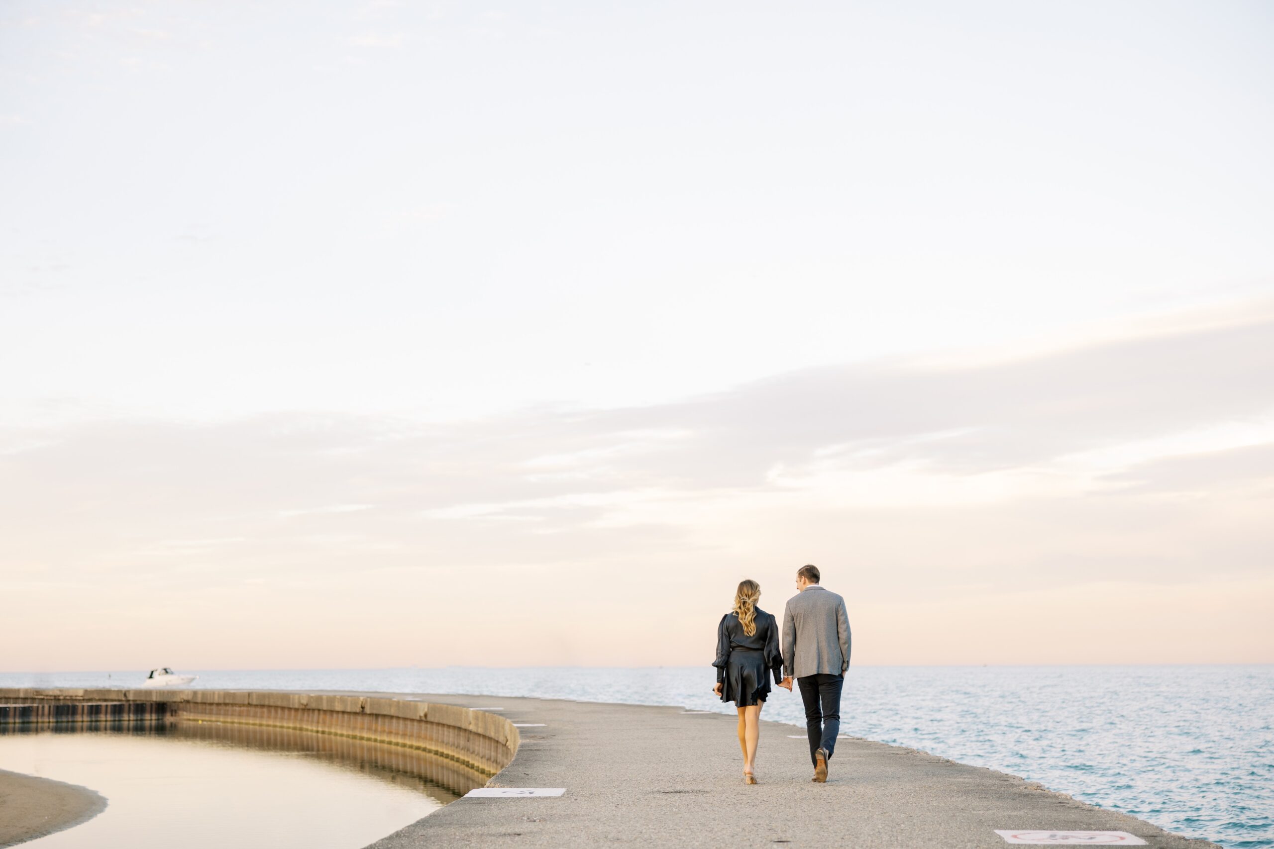 Couple walks holding hands during engagement session at North Avenue Beach