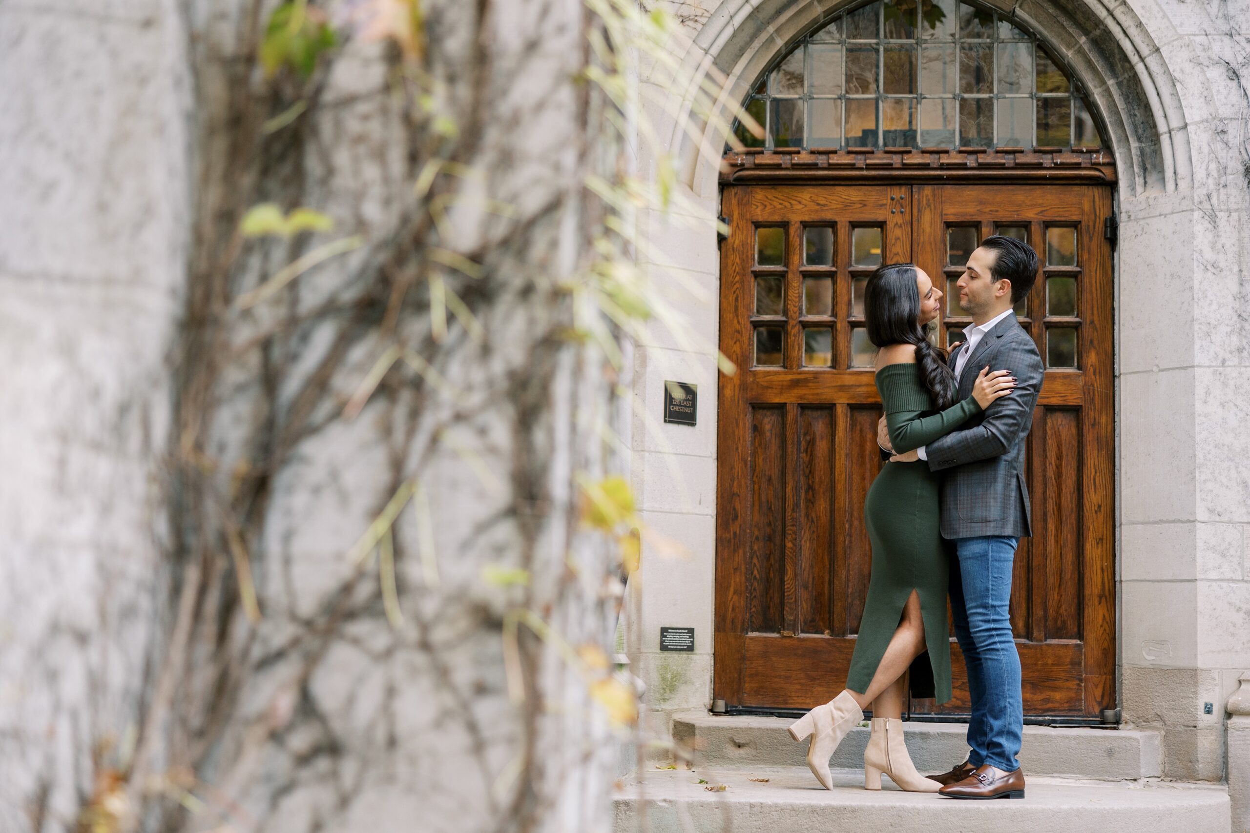 Man and woman stand in front of wooden door during Chicago engagement photos