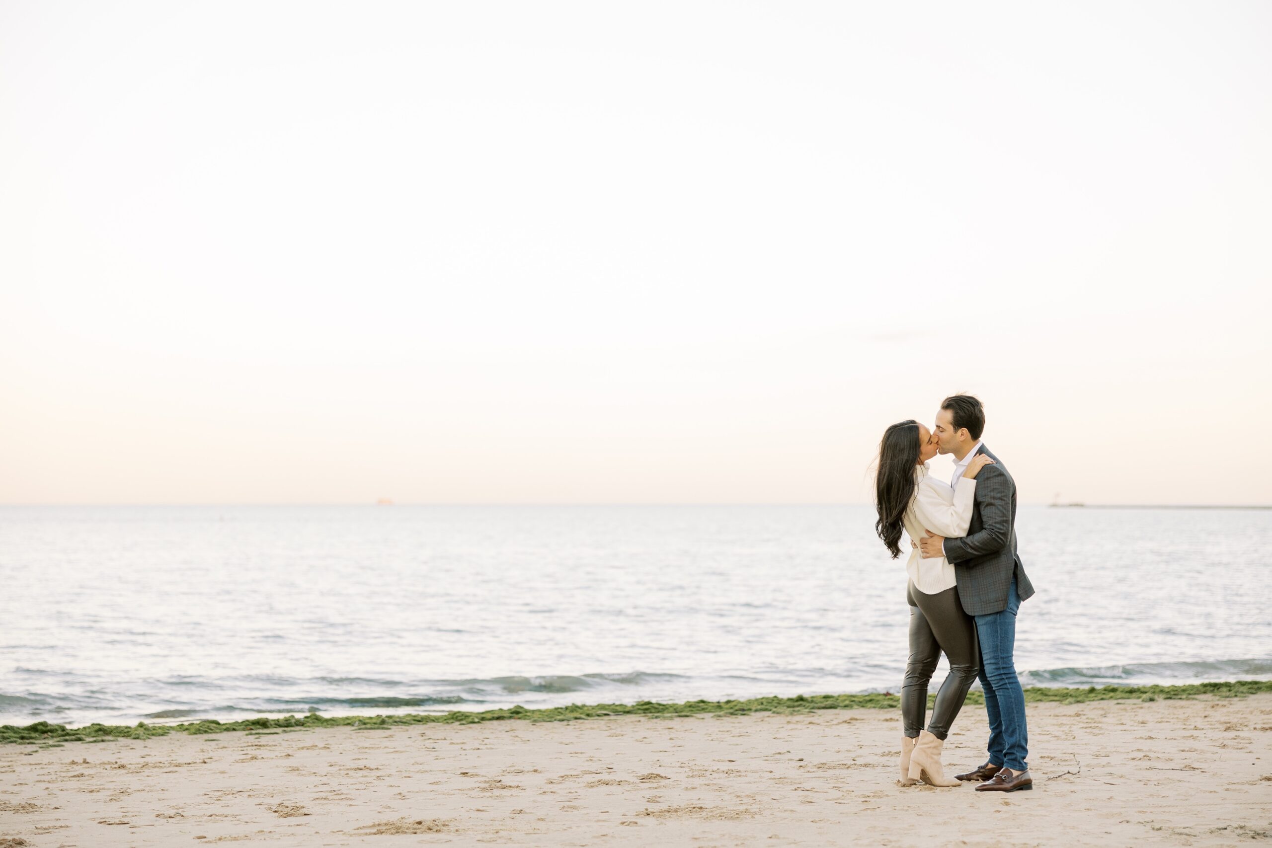Man and woman kiss on the beach during Chicago engagement session